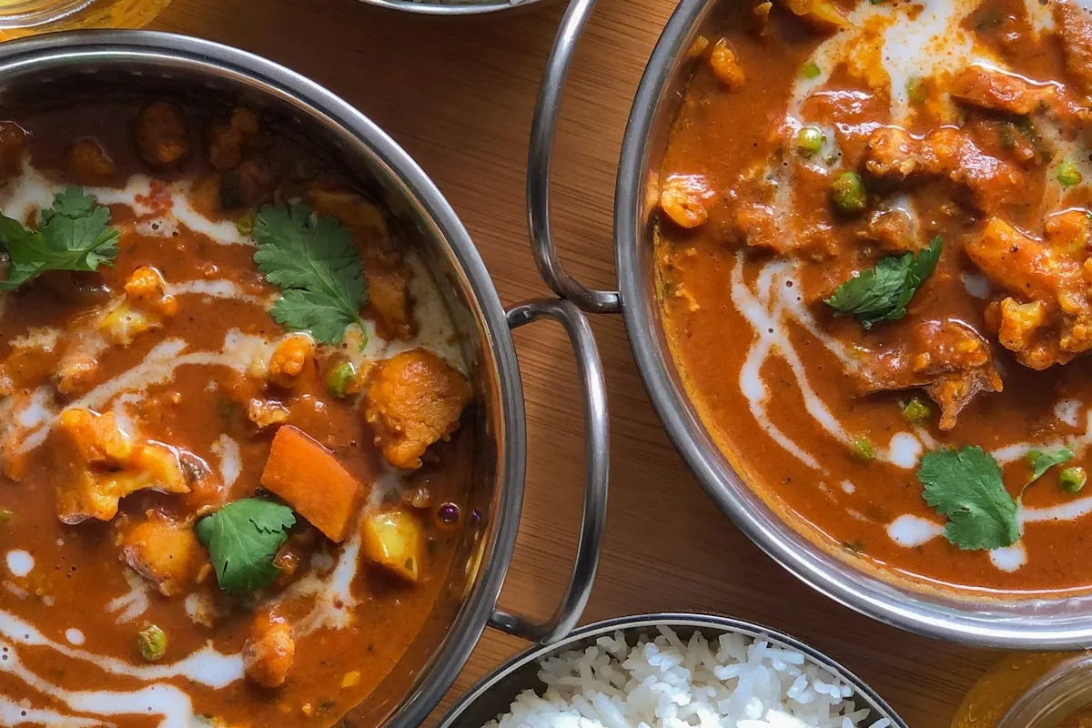 Rich Indian curry with fresh naan bread and sides