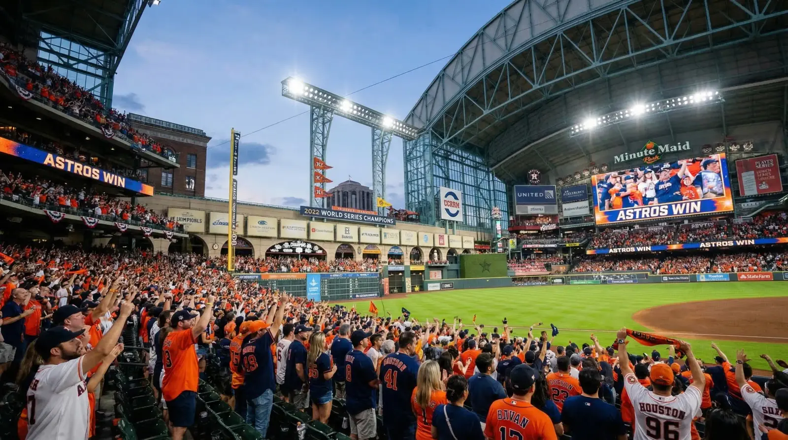 Daikin Park Houston Astros baseball game — packed stadium with fans in orange and navy celebrating, retractable roof open, Union Station facade in left field, World Series champion banners