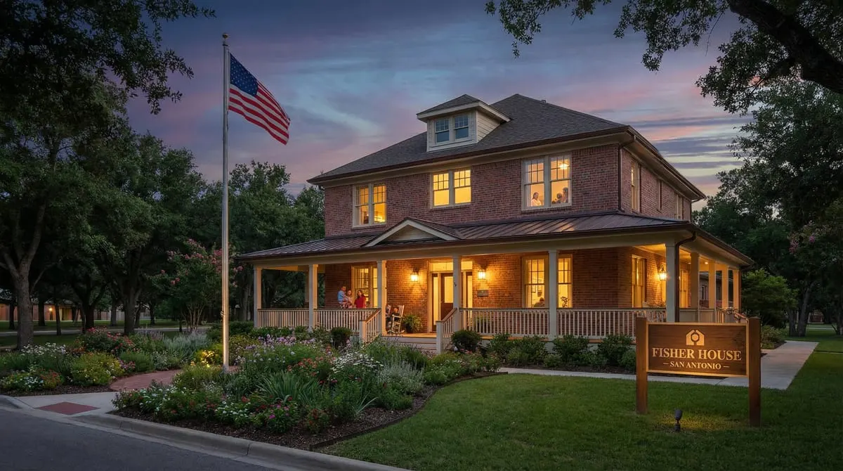 Fisher House comfort home at Fort Sam Houston in San Antonio with American flag, warm porch lighting at dusk, providing free lodging for military families near BAMC